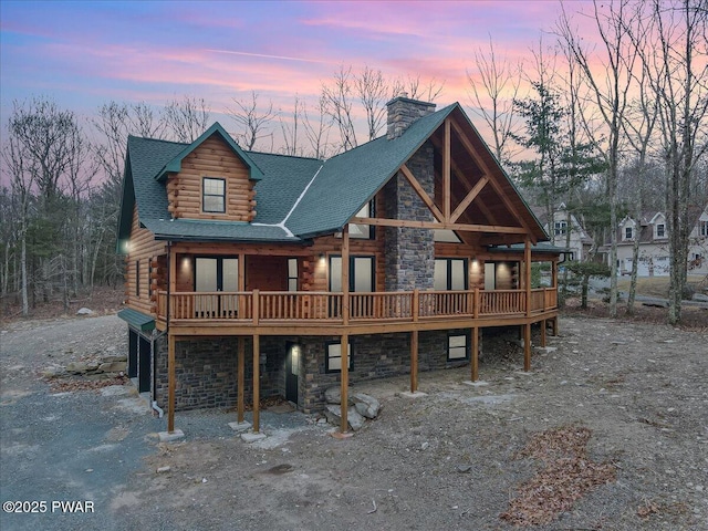 back house at dusk featuring a wooden deck