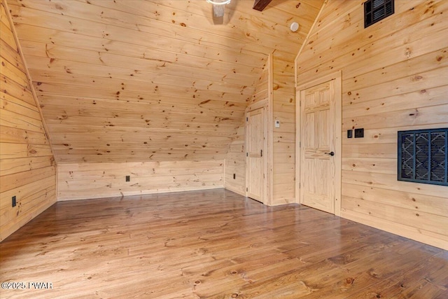 bonus room featuring wood-type flooring, lofted ceiling, and wooden walls