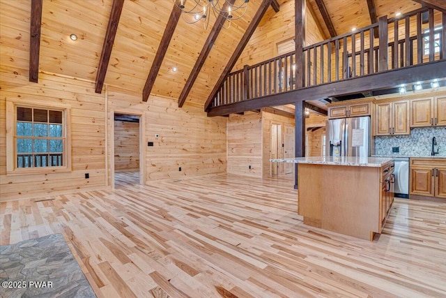 kitchen featuring a center island, light stone countertops, appliances with stainless steel finishes, beam ceiling, and wood ceiling