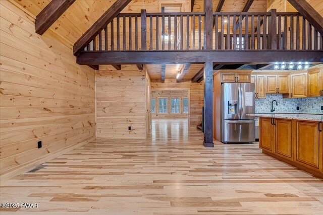 kitchen with beamed ceiling, stainless steel fridge with ice dispenser, wood walls, and wood ceiling