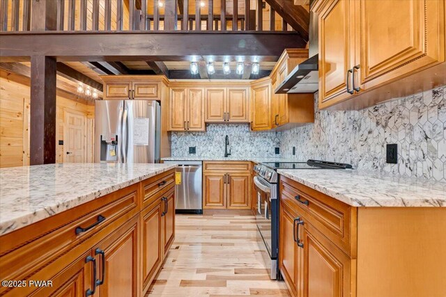 kitchen with backsplash, sink, light hardwood / wood-style flooring, light stone countertops, and appliances with stainless steel finishes