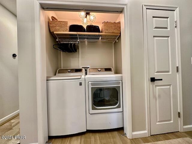 laundry room featuring separate washer and dryer and light hardwood / wood-style flooring