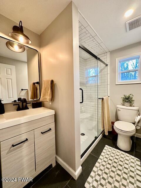 bathroom featuring tile patterned flooring, vanity, an enclosed shower, and toilet