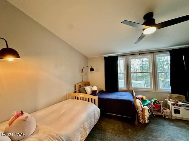 bedroom with ceiling fan, lofted ceiling, and dark colored carpet