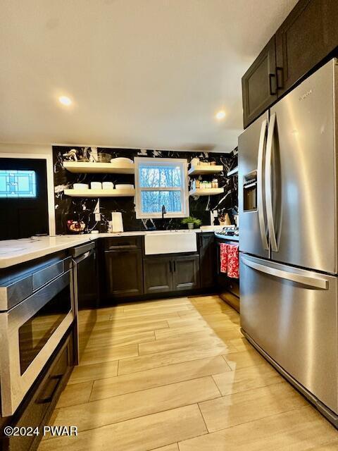 kitchen featuring stainless steel fridge, dark brown cabinets, built in microwave, sink, and light hardwood / wood-style flooring