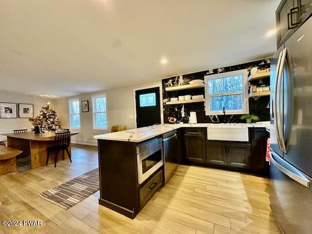 kitchen featuring kitchen peninsula, sink, light wood-type flooring, and appliances with stainless steel finishes