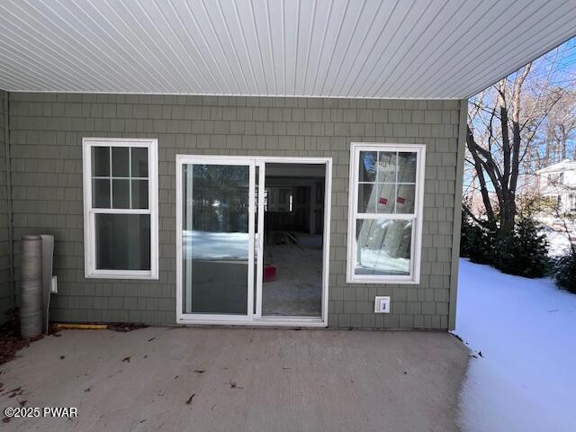 snow covered property entrance featuring a patio