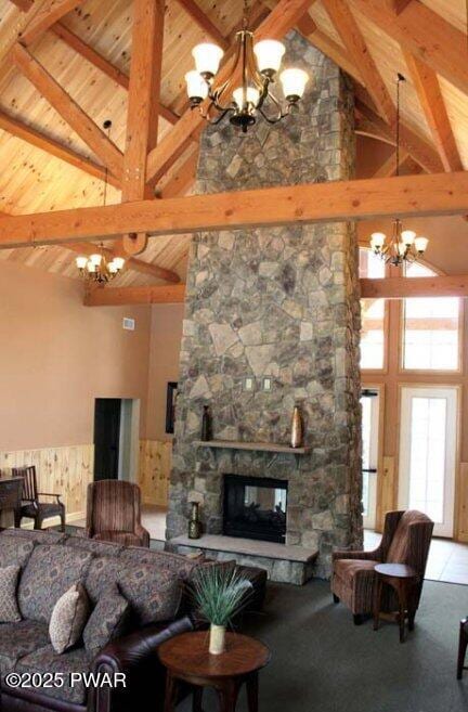 living room with wood ceiling, a stone fireplace, and a chandelier