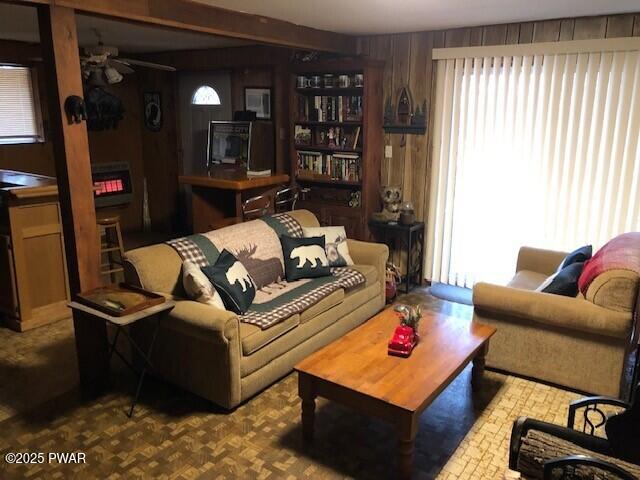 living room featuring wood walls and ceiling fan