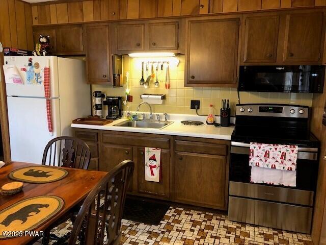 kitchen featuring white refrigerator, tasteful backsplash, stainless steel range with electric cooktop, and sink