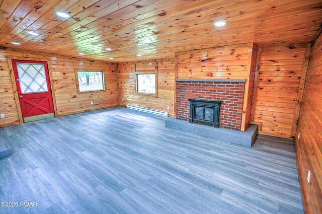 unfurnished living room featuring wood ceiling, baseboard heating, wood walls, wood finished floors, and recessed lighting