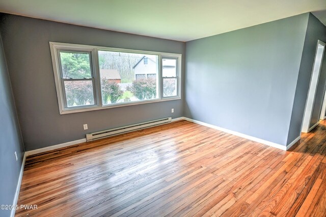 spare room featuring baseboards, a healthy amount of sunlight, hardwood / wood-style flooring, and a baseboard radiator