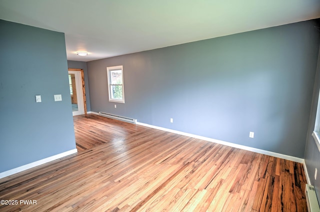 empty room with baseboards, baseboard heating, a baseboard heating unit, and wood finished floors