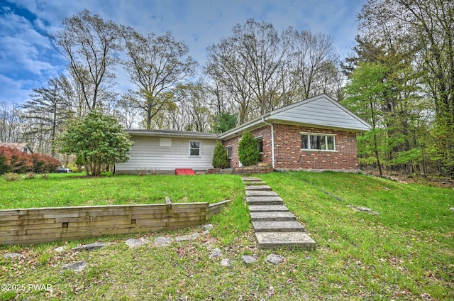 back of property featuring a yard and brick siding