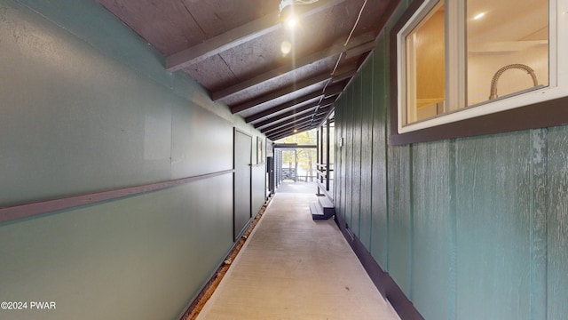 hall featuring vaulted ceiling with beams and wood walls