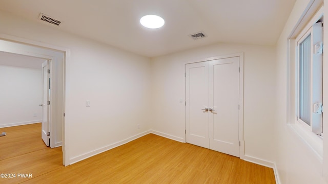 unfurnished bedroom featuring a closet, wood-type flooring, and lofted ceiling