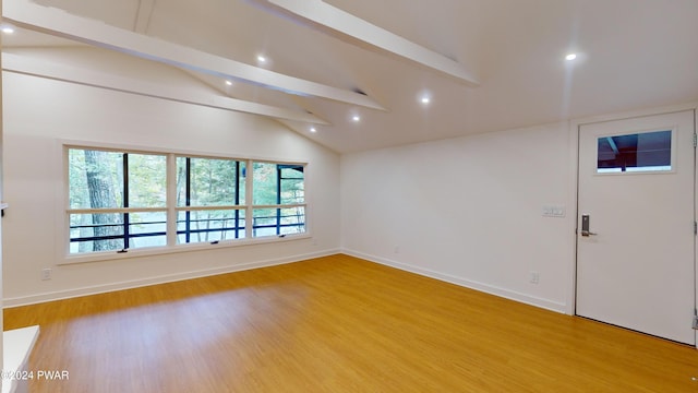 empty room with light wood-type flooring and vaulted ceiling with beams