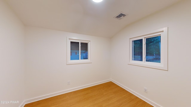 spare room featuring hardwood / wood-style floors and vaulted ceiling