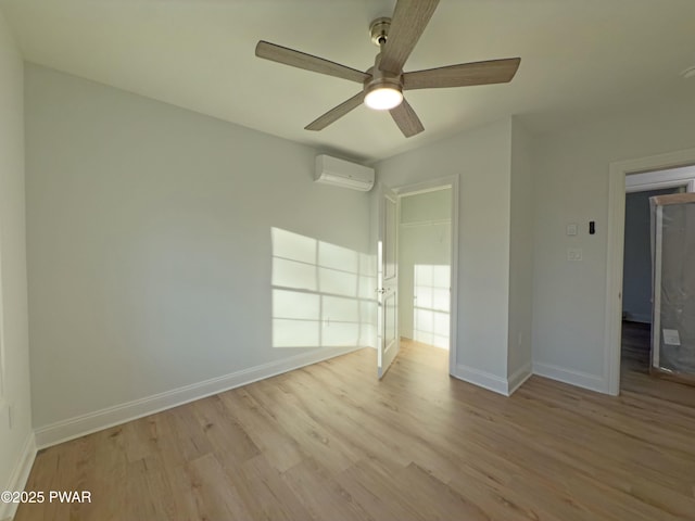 empty room featuring a wall mounted air conditioner, light hardwood / wood-style flooring, and ceiling fan