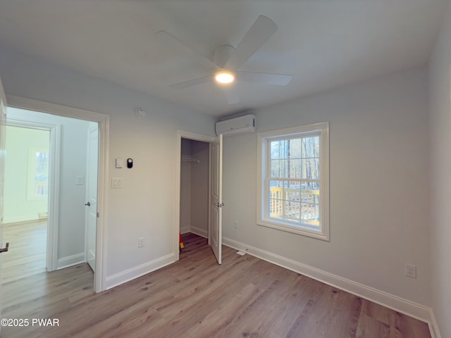 unfurnished bedroom featuring a closet, ceiling fan, light hardwood / wood-style flooring, and a wall unit AC