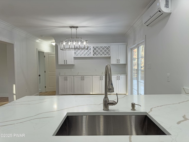 kitchen featuring crown molding, a wall mounted air conditioner, hanging light fixtures, sink, and light stone counters