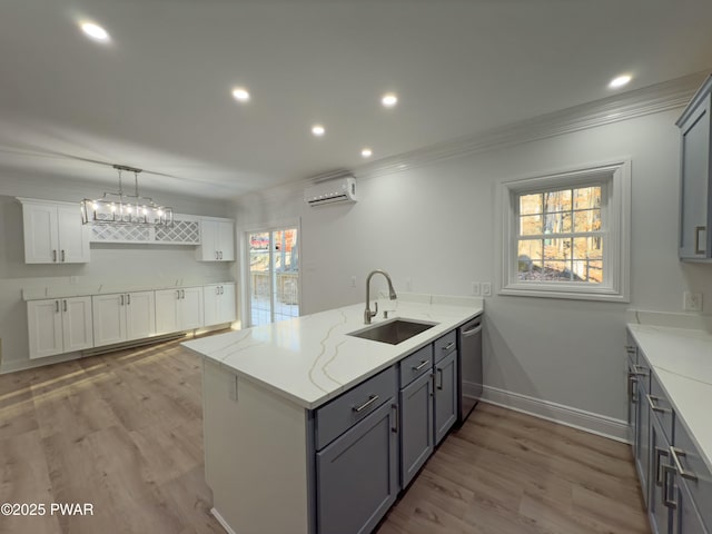 kitchen with kitchen peninsula, sink, white cabinets, light stone counters, and an AC wall unit