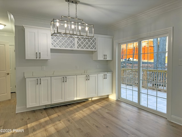 interior space featuring light wood-type flooring, white cabinetry, hanging light fixtures, and ornamental molding