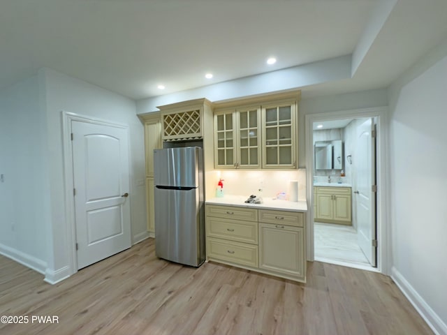 kitchen with light hardwood / wood-style flooring, cream cabinets, and stainless steel refrigerator