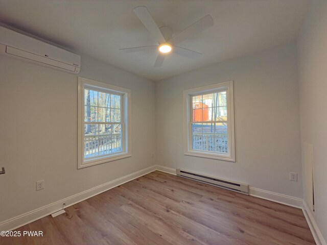 empty room with light hardwood / wood-style floors, a baseboard radiator, plenty of natural light, and a wall mounted AC