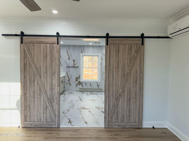 interior space with a barn door, hardwood / wood-style floors, crown molding, and a wall unit AC