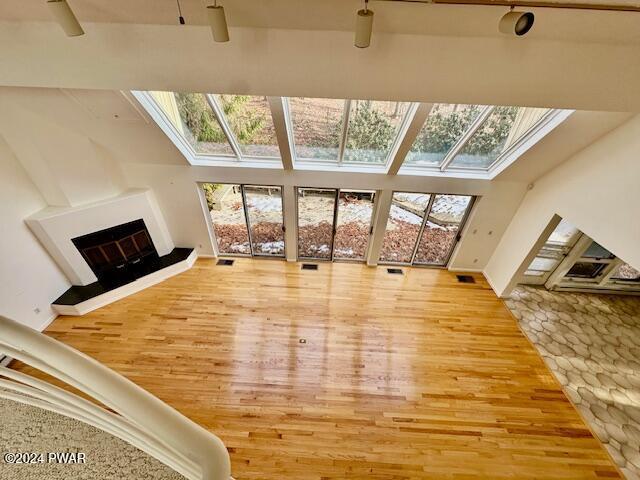 living room with a healthy amount of sunlight, wood-type flooring, and lofted ceiling with skylight