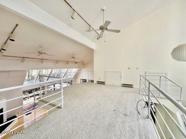 unfurnished living room with lofted ceiling with beams, rail lighting, and light colored carpet