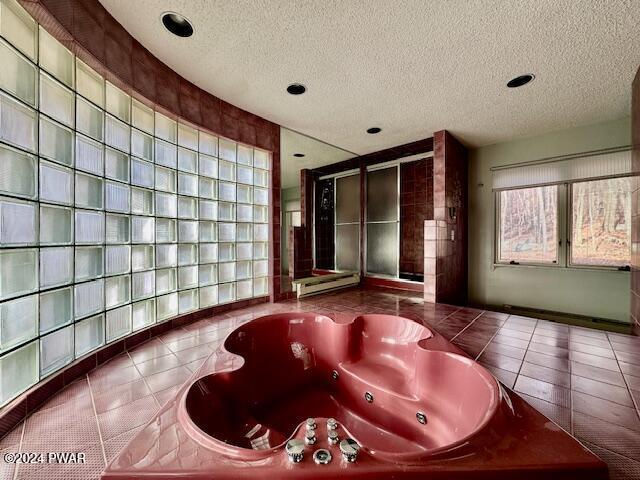 bathroom featuring tile patterned floors, a bathtub, a textured ceiling, and a baseboard heating unit