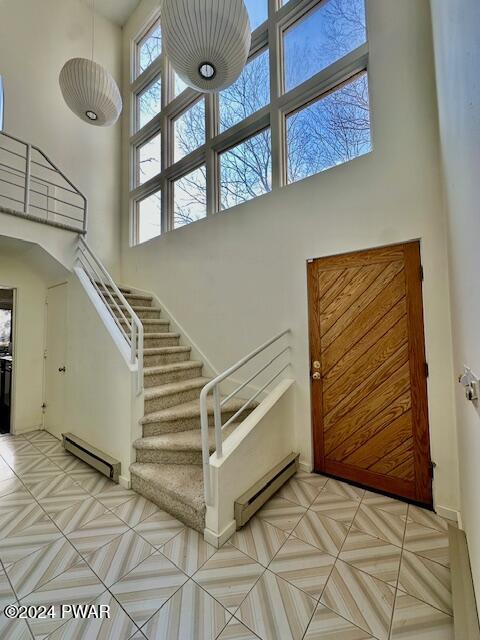 stairs featuring a towering ceiling and a baseboard radiator