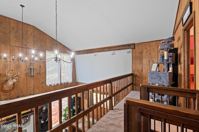 corridor featuring carpet flooring, a notable chandelier, wood walls, and vaulted ceiling