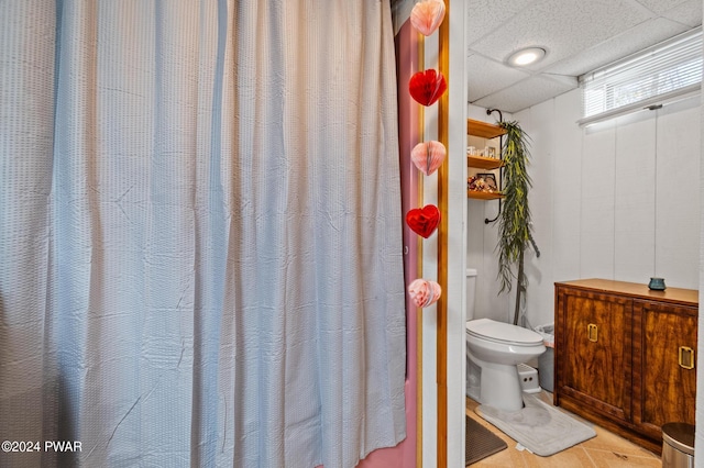 bathroom featuring toilet and a drop ceiling