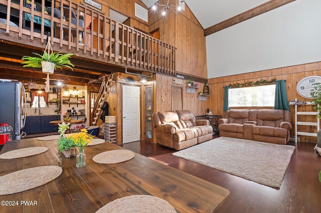 living room with dark hardwood / wood-style floors, high vaulted ceiling, and wooden walls