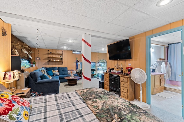 living room featuring a paneled ceiling and wooden walls