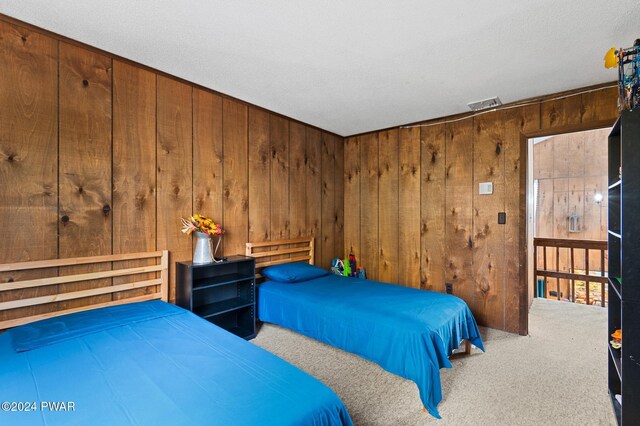 bedroom featuring wood walls, carpet, and a textured ceiling