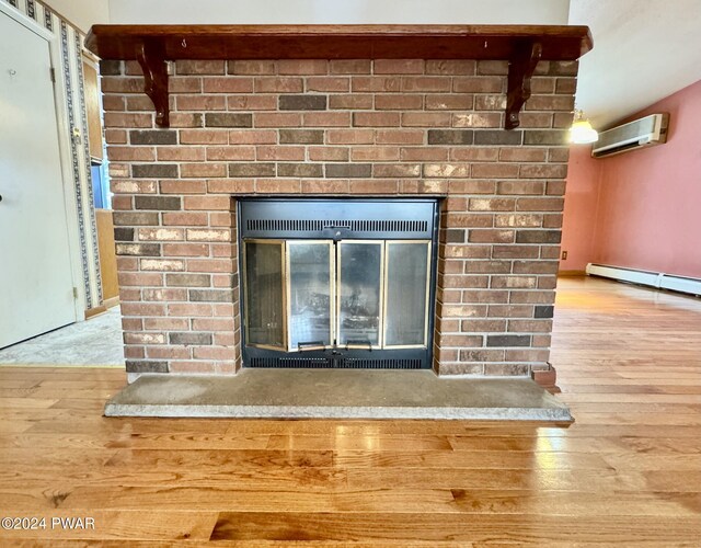 details featuring hardwood / wood-style flooring, a brick fireplace, a wall mounted AC, and a baseboard radiator