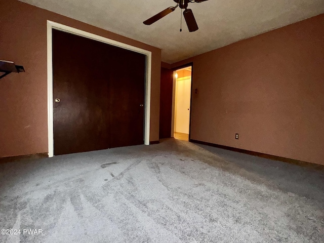 unfurnished bedroom with carpet, a textured ceiling, a closet, and ceiling fan