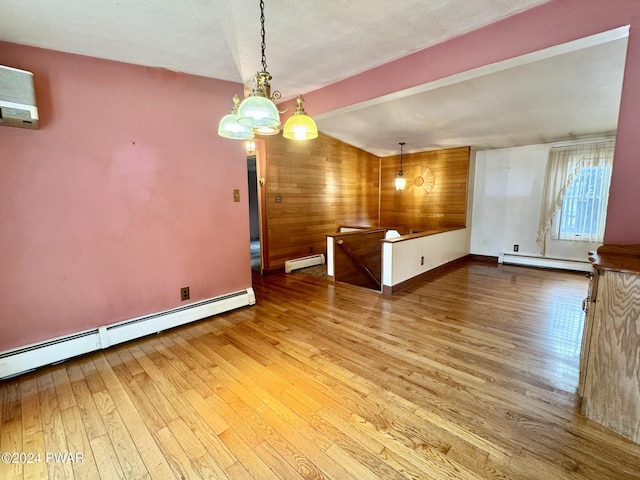 unfurnished dining area featuring wood walls, light wood-type flooring, and baseboard heating