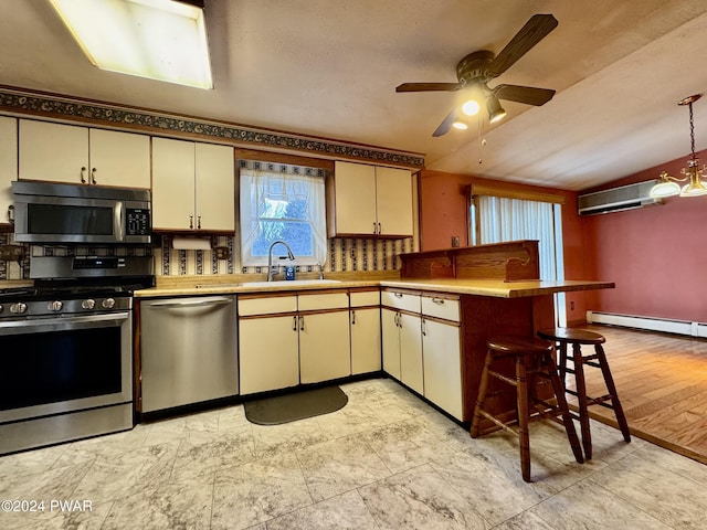 kitchen featuring sink, hanging light fixtures, stainless steel appliances, kitchen peninsula, and cream cabinetry