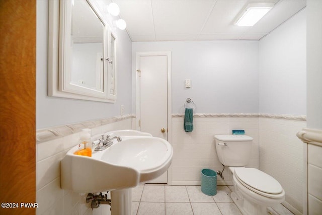 bathroom featuring tile patterned floors, toilet, and tile walls