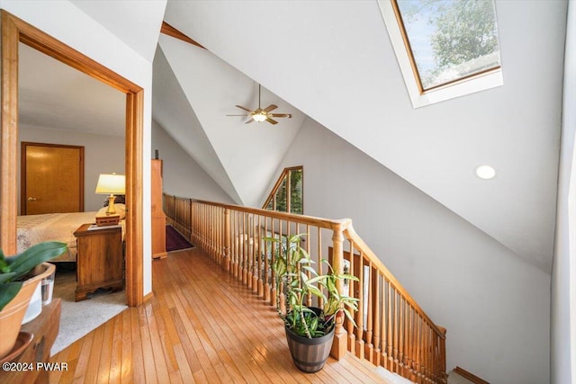 hall featuring vaulted ceiling with skylight and wood-type flooring