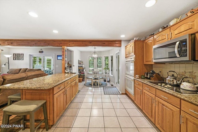 kitchen featuring backsplash, double oven, stovetop, pendant lighting, and a kitchen island