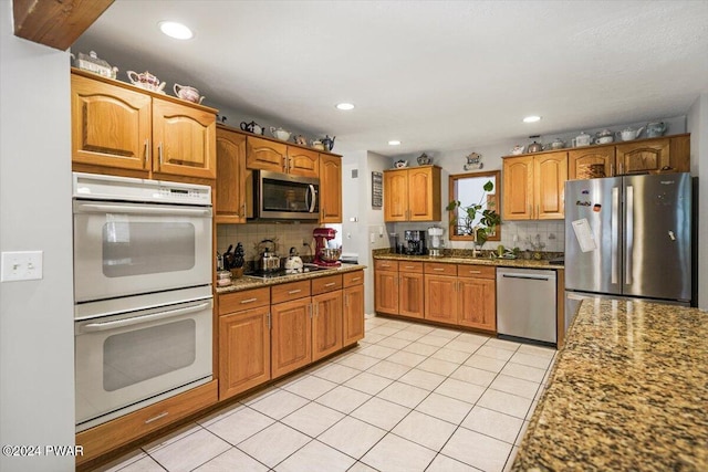 kitchen featuring light stone countertops, sink, light tile patterned floors, and stainless steel appliances