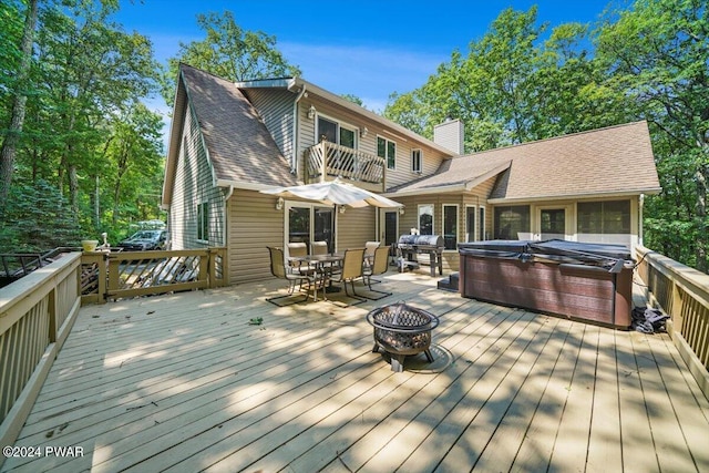 wooden terrace with a fire pit, area for grilling, and a hot tub