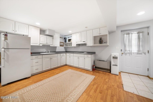 kitchen featuring white fridge, white cabinetry, sink, and light hardwood / wood-style flooring