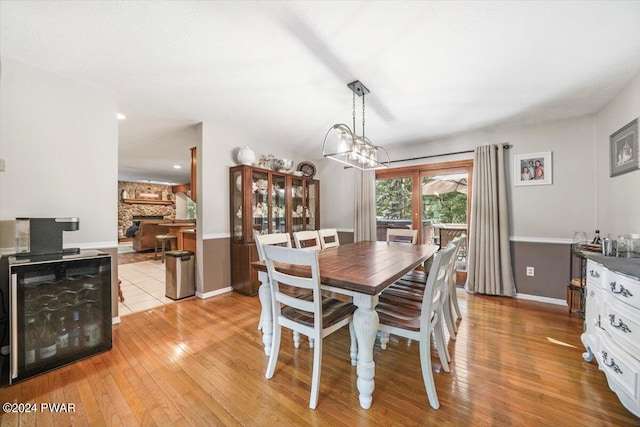 dining space with a notable chandelier, a stone fireplace, and light wood-type flooring